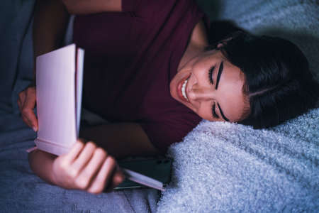 Young woman reading book in bedの写真素材