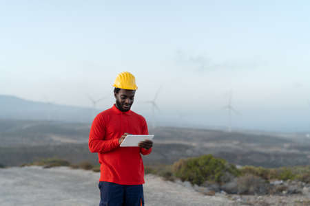 African engineer working with tablet on construction site - Technology and industry concept