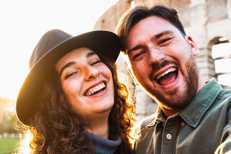 Happy young couple taking selfie in front of Rome Colosseum during vacations