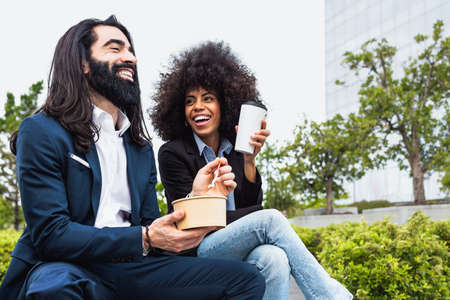Happy multiracial business people having a lunch break outside office