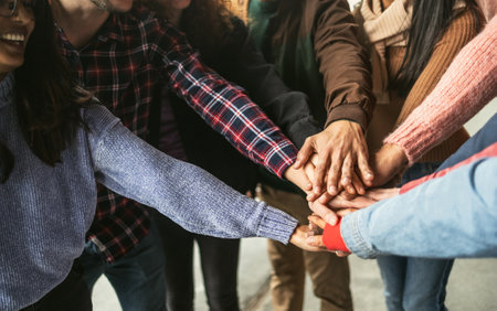 Happy young friends having fun stacking hands together outdoor - Youth people millennial generation...