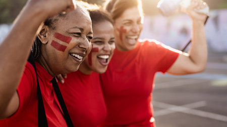 Female football fans exulting while watching soccer game at stadium - Women with painted face and megaphone encouraging their team - Sport entertainment conceptの写真素材