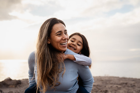 Happy Latin mother enjoying time with her child on the beach - Family and love conceptの写真素材