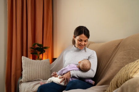 Happy mother taking care of her little baby sleeping in her arms at home - Concept family and motherhoodの写真素材