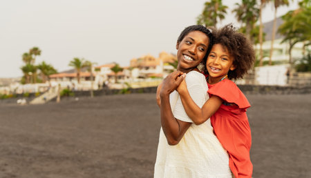 Happy African mother and daughter having fun on the beach during vacations - Lovely family lifestyle conceptの写真素材