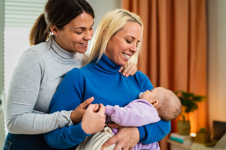 Happy lesbian couple having tender moments with their little baby at home - Family and maternity conceptの写真素材