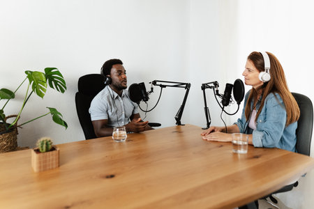 Multiracial people recording a podcast using microphone and headphones from home studioの写真素材