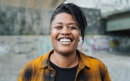Happy African woman smiling in front of a camera in the cityの写真素材
