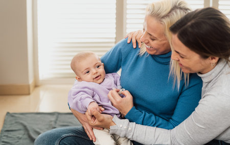 Happy lesbian couple having tender moments with their small baby at home - LGBT Family conceptの写真素材