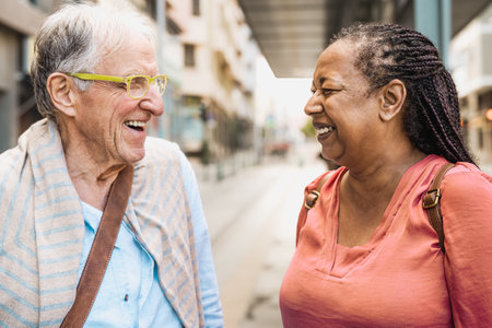 Happy multiracial senior friends talking while waiting at the bus stationの写真素材