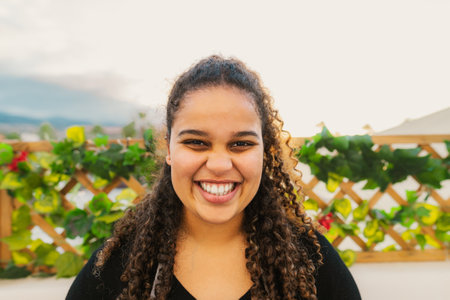 Happy young African girl having fun smiling in front of camera on house patioの写真素材