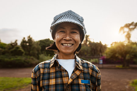 Happy Southeast Asian woman having fun smiling on camera in a public parkの写真素材