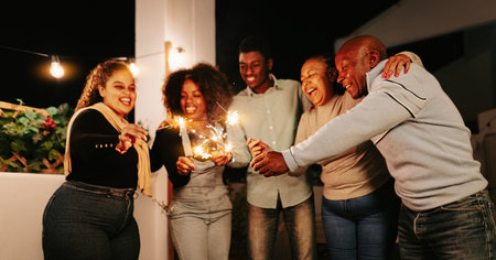 Happy African family celebrating with sparklers fireworks at house party - Parents and holidays conceptの写真素材