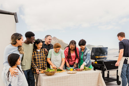 Multigenerational friends having fun doing barbecue at house rooftop - Happy multiracial people cooking together - Summer gatherings and food conceptの写真素材