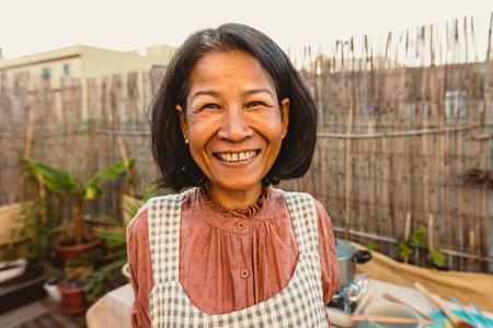 Happy Thai woman having fun smiling in front of camera while preparing food recipe at house patioの写真素材