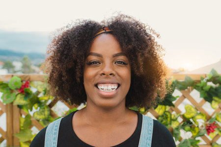 Happy young African girl having fun smiling in front of camera on house patioの写真素材