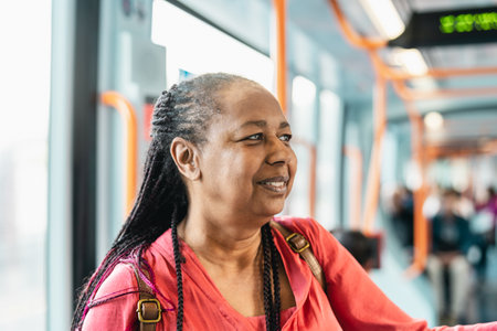 Happy African senior woman traveling with public tramの写真素材