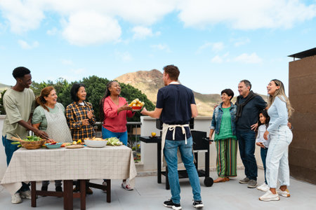 Multigenerational friends having fun doing barbecue at house rooftop - Happy multiracial people cooking togetherの写真素材