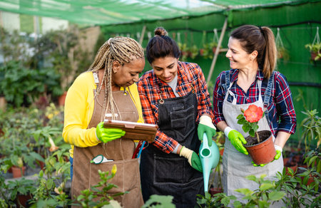 Happy multiracial women working together in plants and flowers garden shopの写真素材
