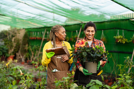Happy multiracial women working together in plants and flowers garden shopの写真素材