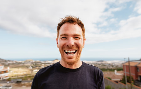 Happy Caucasian young man smiling in front of camera at house rooftopの写真素材
