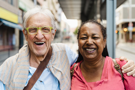 Happy multiracial senior friends having fun while waiting at the bus stationの写真素材