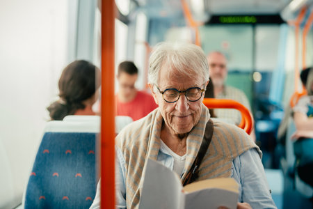 Senior man reading book while traveling with busの写真素材