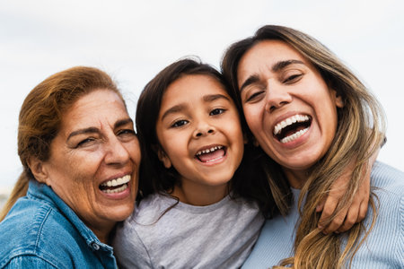 Happy Hispanic multigenerational family smiling into the camera - Child having fun with her mother and grandmother outdoorの写真素材