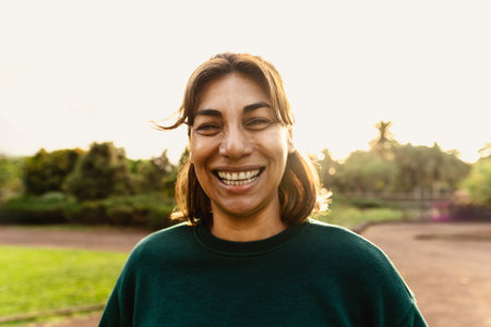 Happy Latin woman having fun smiling in the camera in a public parkの写真素材
