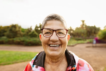 Happy senior woman having fun smiling in front of camera after training activity in a public parkの写真素材