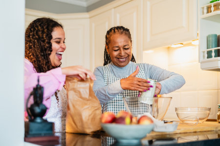 Happy African mother and daughter having fun preparing a homemade dessertの写真素材