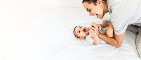 Happy joyful mother having fun with her small baby on bed - Family and motherhood conceptの写真素材