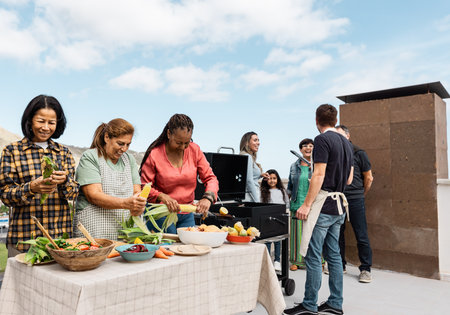 Multigenerational friends having fun doing barbecue at house rooftop - Happy multiracial people cooking togetherの写真素材