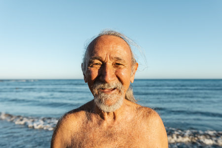 Happy elderly man having fun on the beach during summer vacation