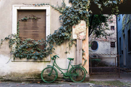 Old green bike in a street of Bresciaの写真素材