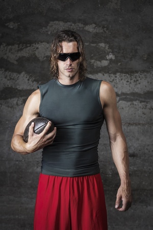 muscle man is wearing sunglasses and holding football ballの写真素材