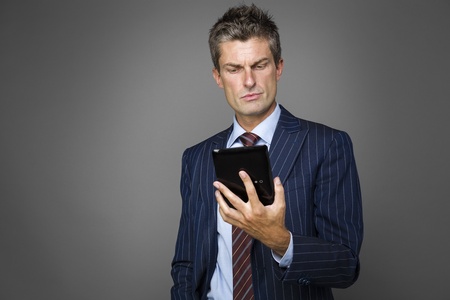 Portrait of elegant pensive businessman watching news on his tabletの写真素材