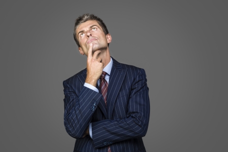 Portrait of elegant pensive businessman looks up looking for answersの写真素材