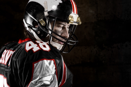 Portrait of thoughtful american football player on dark backgroundの写真素材