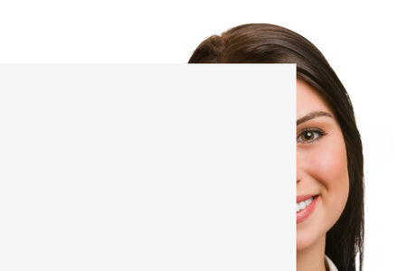 Portrait of half face smiling young woman showing blank signboardの写真素材