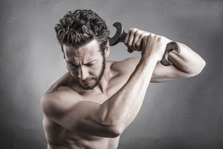 Power bare chest man using a spanner or wrench as a weapon beating down with blows on something...