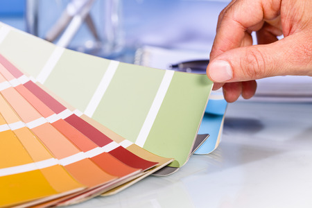 Close up of Artist hand browsing color samples in palette in studio background Close up of Artist hand browsing color samples in palette in studio background