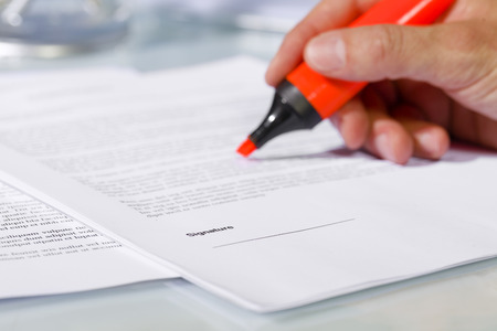 Close-up of man hand with highlighter over document, checking the content before signing. Concept of business and agreementの写真素材