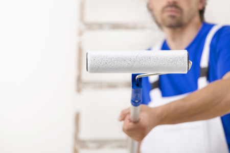 Close up shot of painter man aiming at you with paint roller.の写真素材