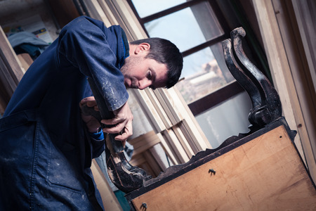 Portrait of Carpenter restoring Wooden Furniture with sandpaper in his workshop.の写真素材