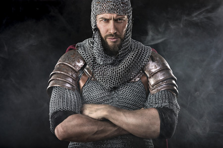 Portrait of Medieval Dirty Face Warrior with chain mail armour. Smoke Cloud on Dark Backgroundの写真素材