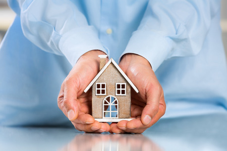 Male hands saving Miniature House on Desktop. Insurance Concept. Insulation Conceptの写真素材