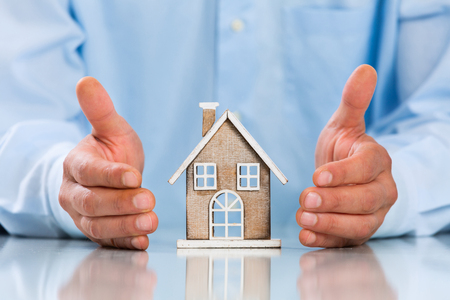 Male hands saving Miniature House on Desktop. Insurance Concept. Insulation Conceptの写真素材