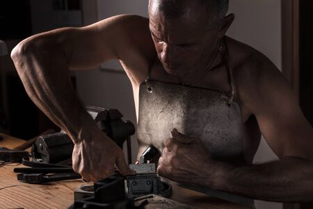 Muscular Middle Aged Artisan working with Metal Vise at his Workshop