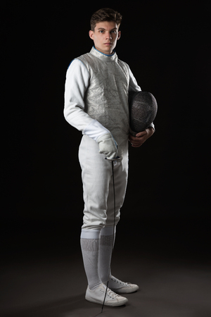 Portrait of Handsome Young male fencer in white fencing costume against Dark Backgroundの写真素材